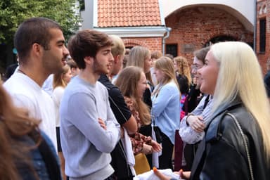 Students are playing a get-to-know-each-other game in the courtyard of the VU Kaunas Faculty.   